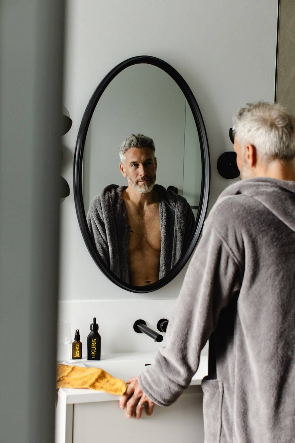 Man at a mirror with KURK products on the sink